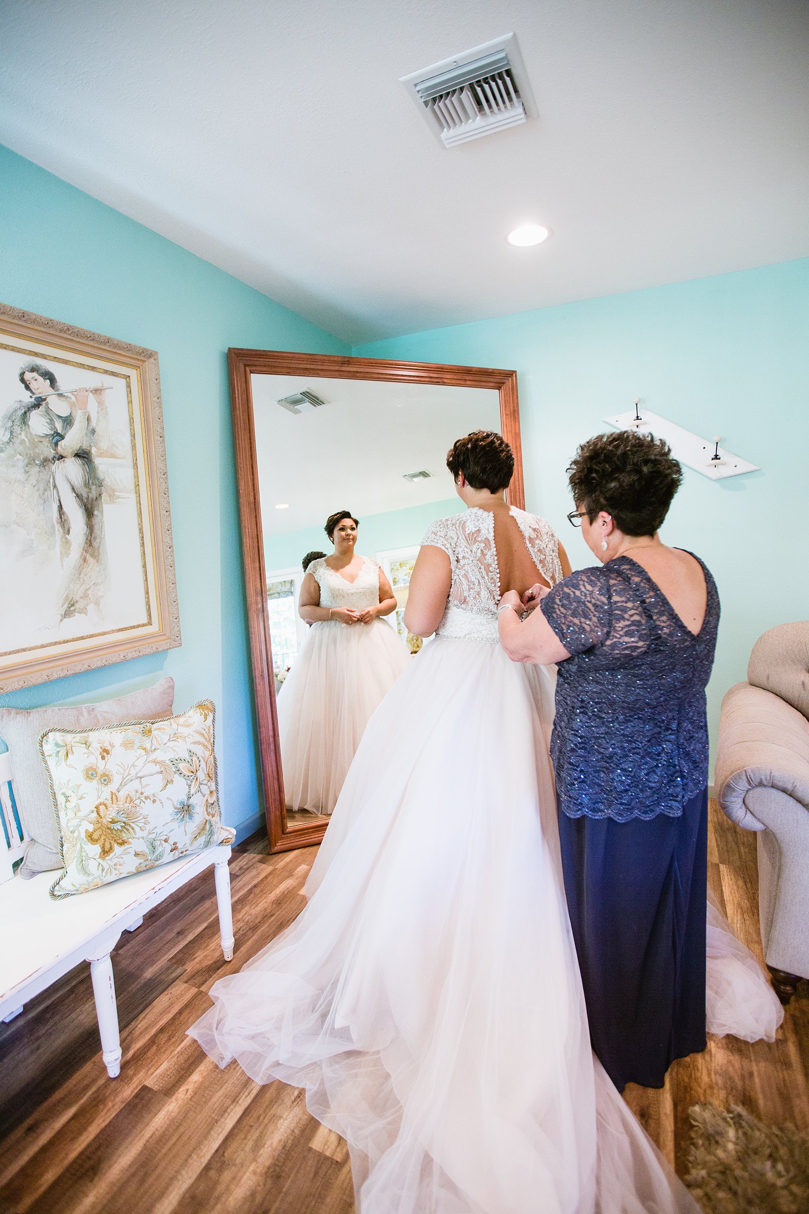 Bride putting on her wedding dress at the Windmill Winery venue bridal suite by PMA Photography.