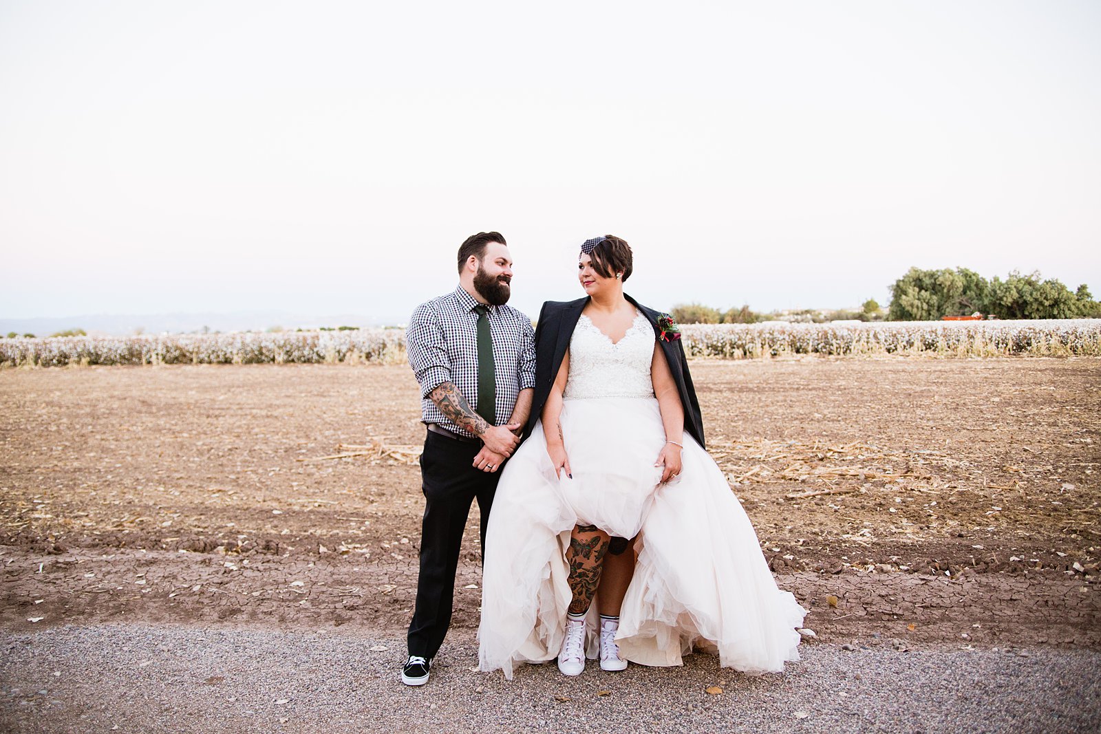 Tattooed bride and groom look at each other by Phoenix wedding photographer PMA Photography.
