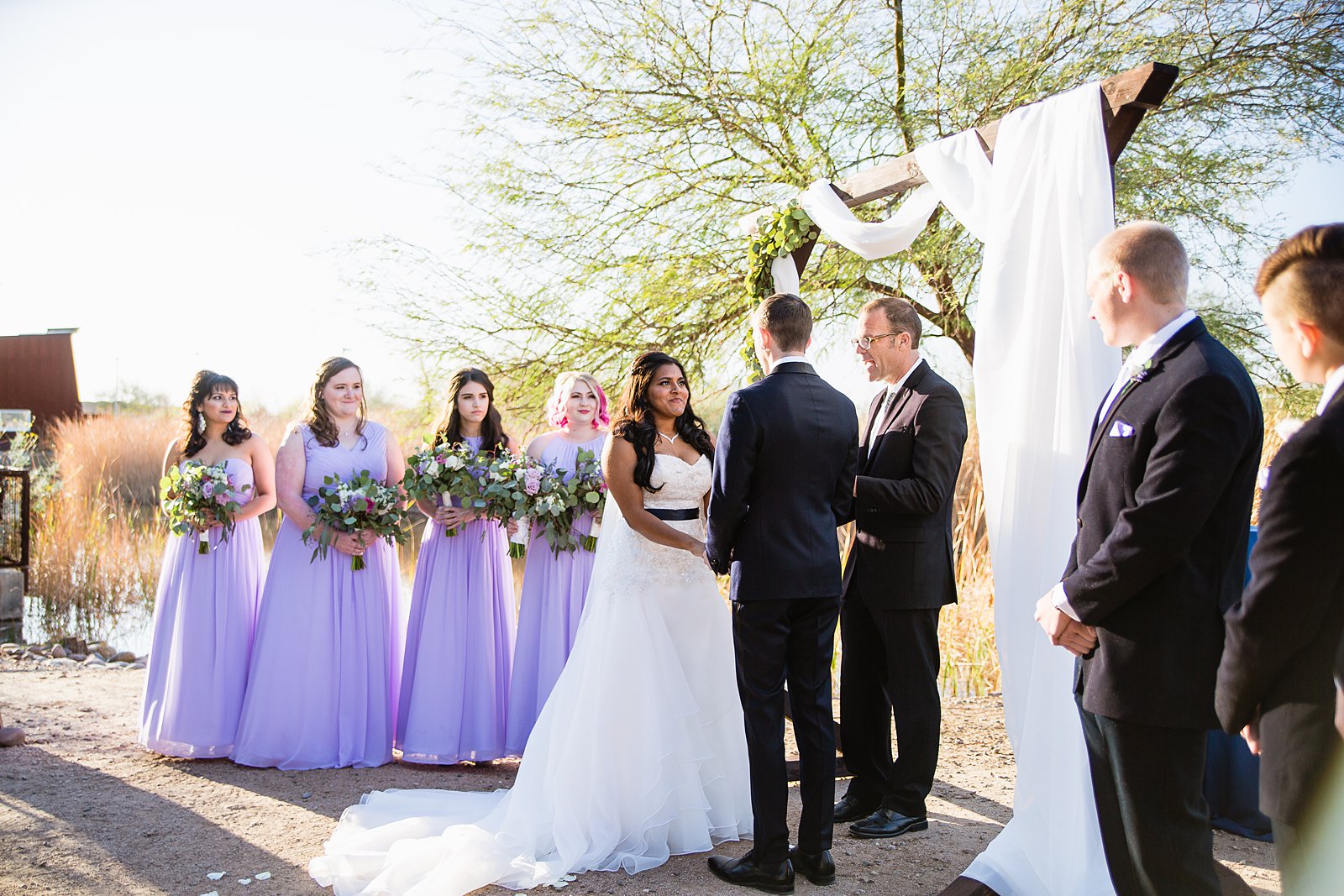 Bride with bridesmaids during Arizona outdoor wedding ceremony by Phoenix wedding photographer PMA Photography.