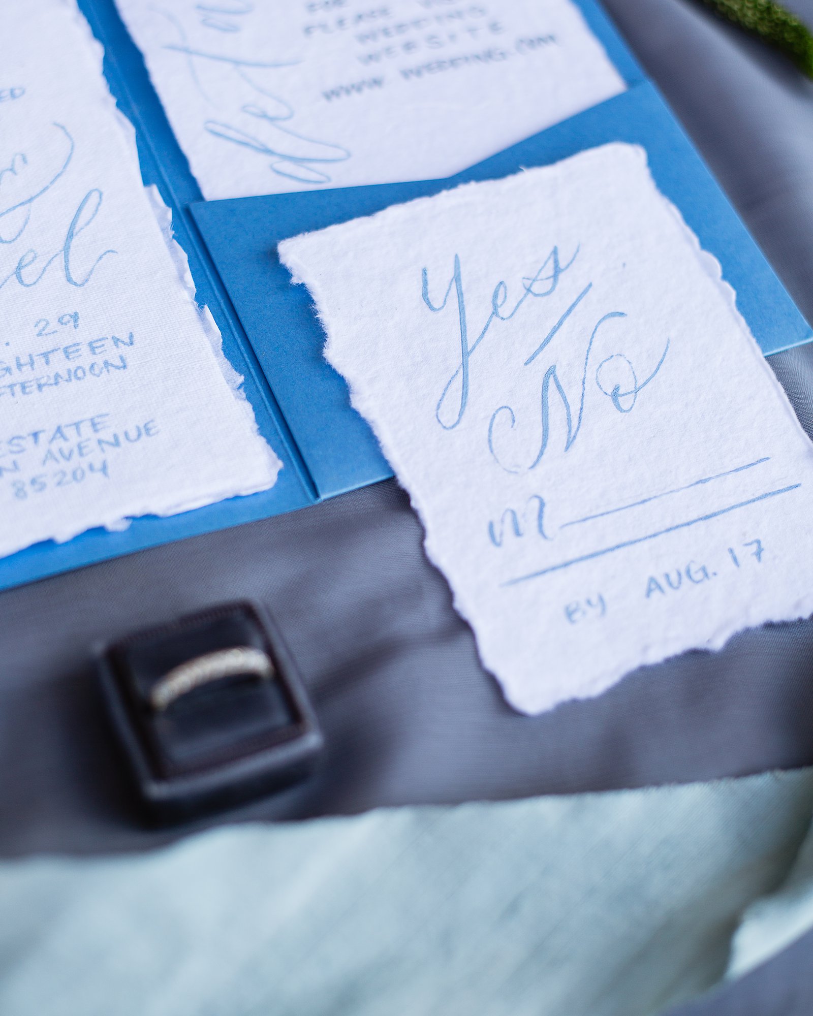 White and blue wedding invitations and stationary lay flat image by PMA Photography.