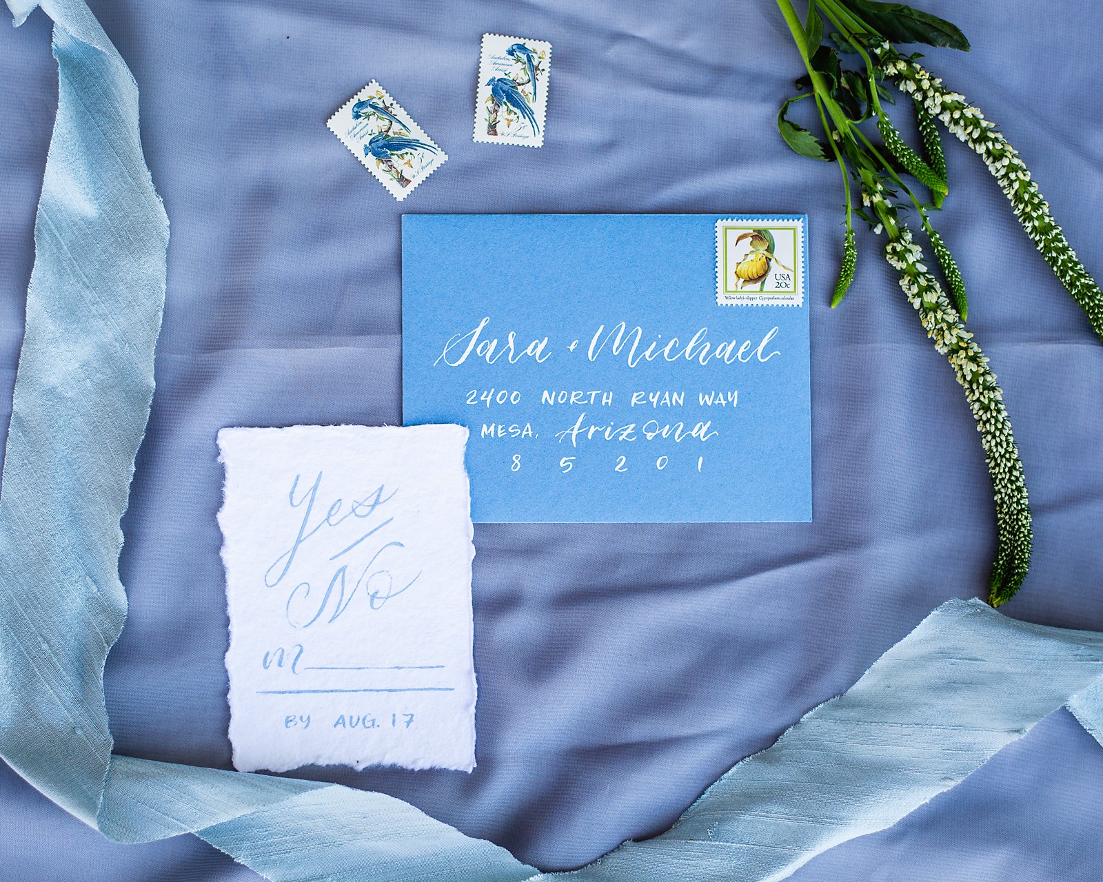 White and blue wedding invitations and stationary lay flat image by PMA Photography.