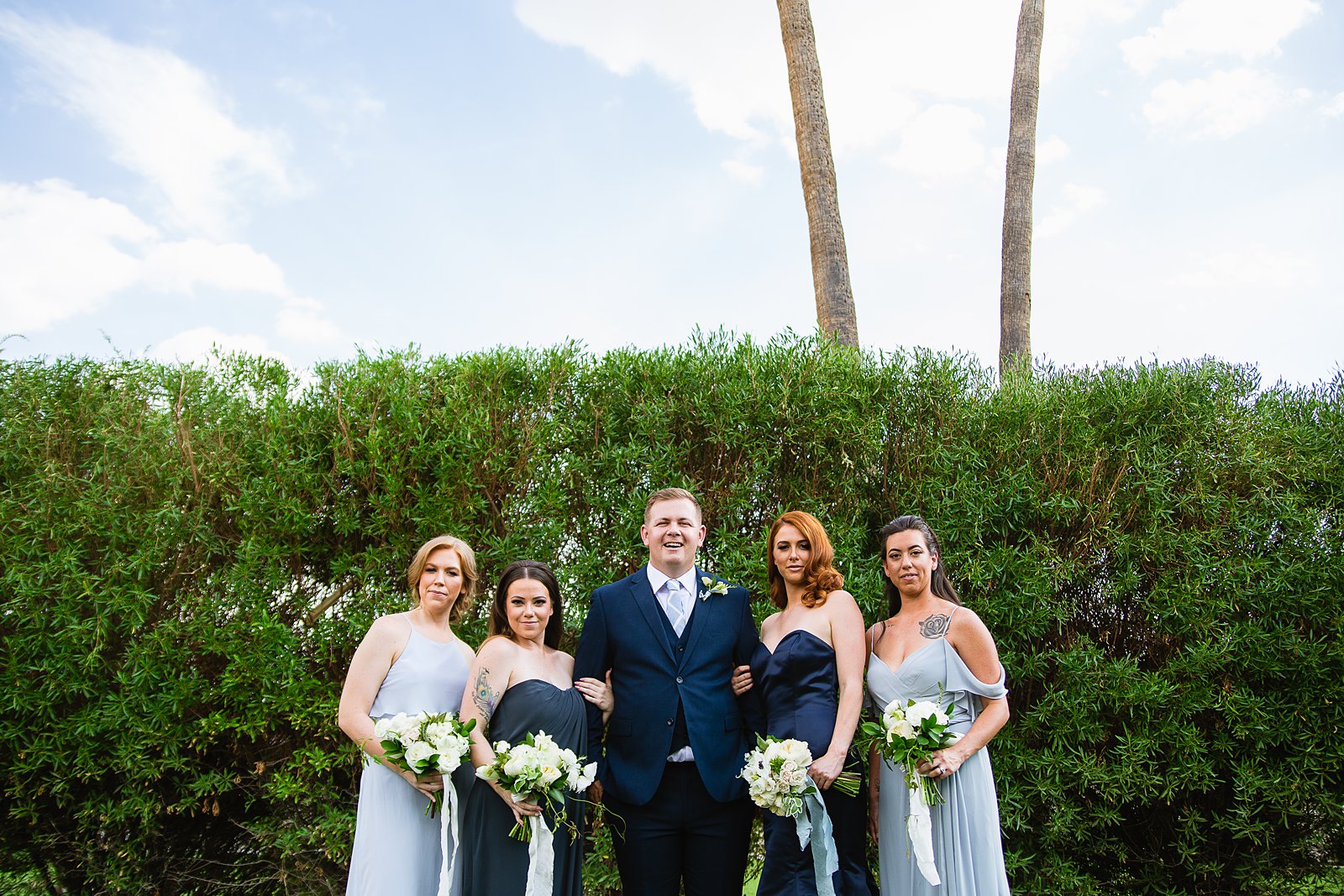 Mixed gender navy and dusty blue bridal party pose together at Gather Estate wedding by Phoenix wedding photographer PMA Photography.