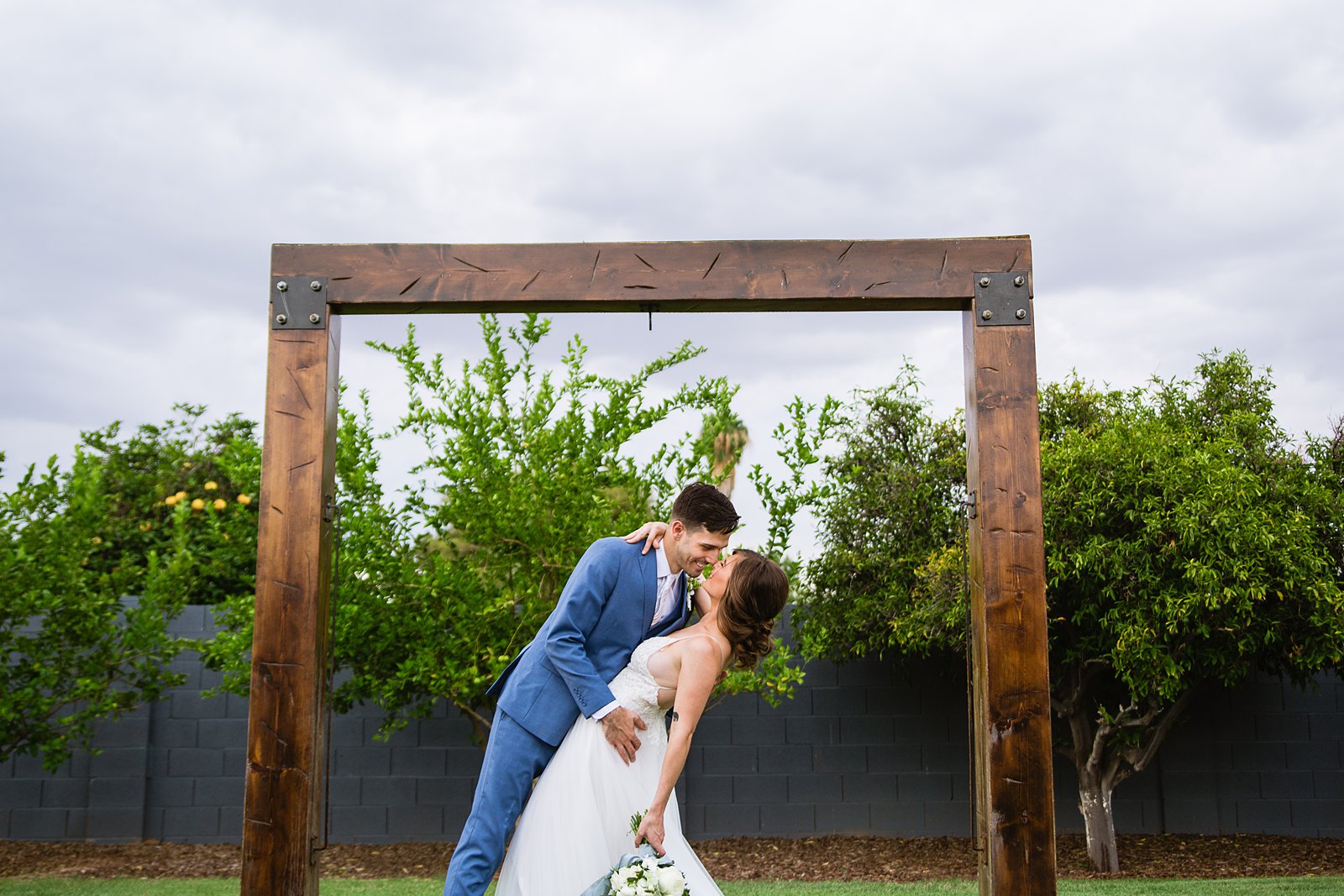 Bride and groom share a kiss under a rustic alter at Gather Estate wedding venue by Arizona wedding photographer PMA Photography.