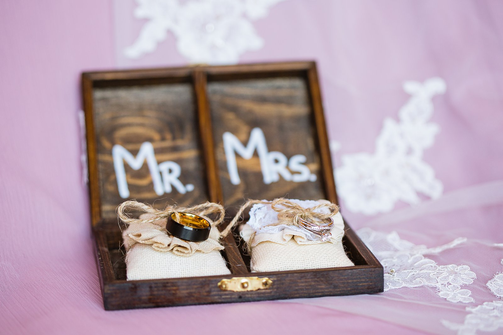 Bride and groom's wedding bands in rustic ring holder by PMA Photography.