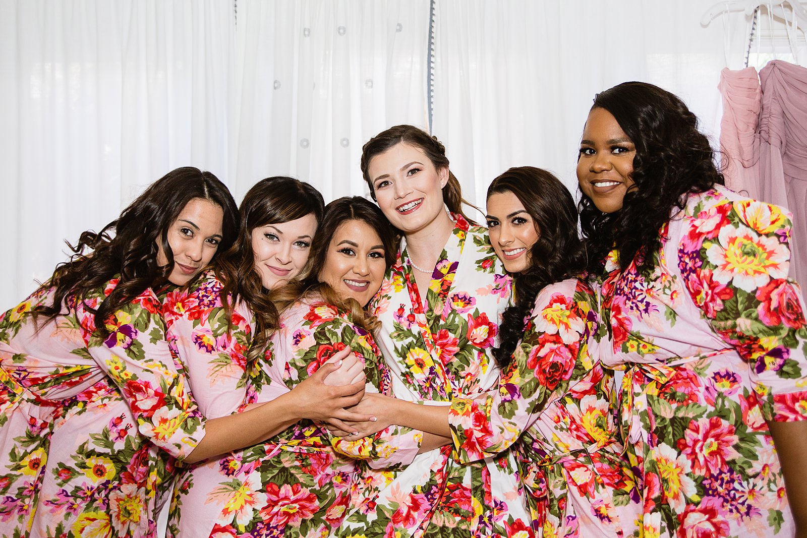 Bride with her bridesmaids in floral robes while getting ready for the wedding by PMA Photography.