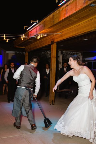 Bride chasing groom with a belt at the wedding reception during a cultural tradition at Schnepf Farms wedding by PMA Photography.