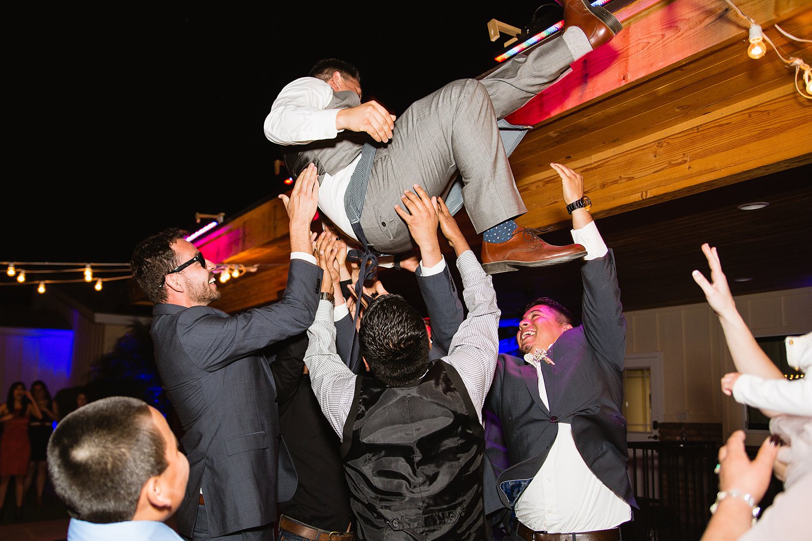 Guests tossing groom at the wedding reception during a cultural tradition at Schnepf Farms wedding by PMA Photography.