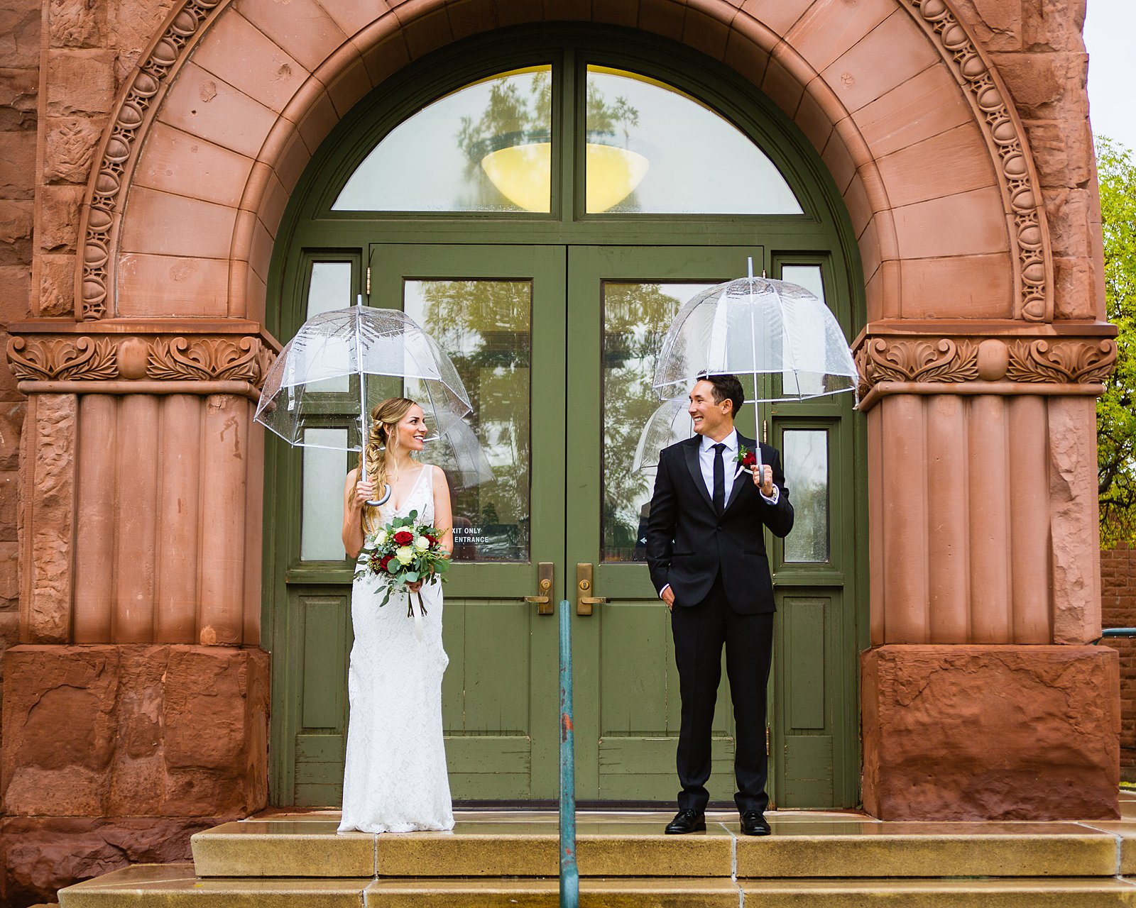 Bride and groom pose during their rainy Flagstaff Courthouse wedding by Arizona wedding photographer PMA Photography.