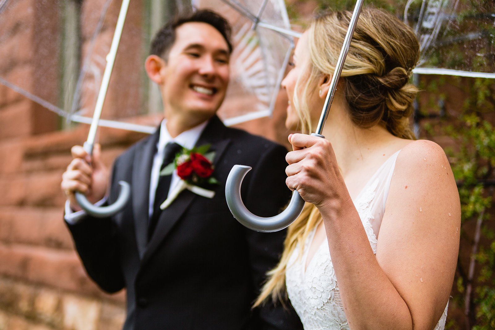 Bride and groom holding umbrellas on their rainy wedding day by Flagstaff wedding photographer PMA Photography.