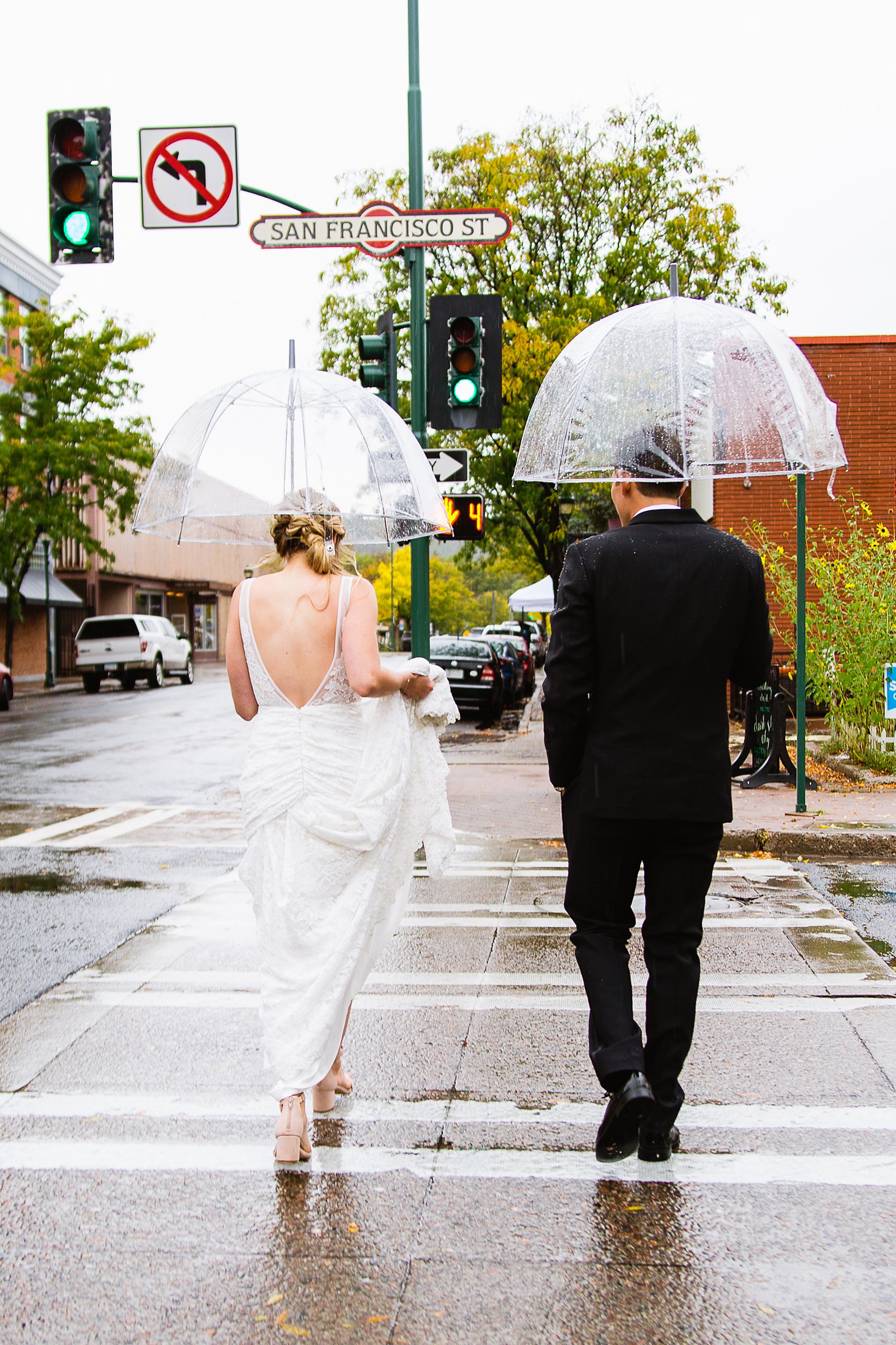 Bride and groom walk through downtown Flagstaff together during their rainy wedding day by Arizona wedding photographer PMA Photography.