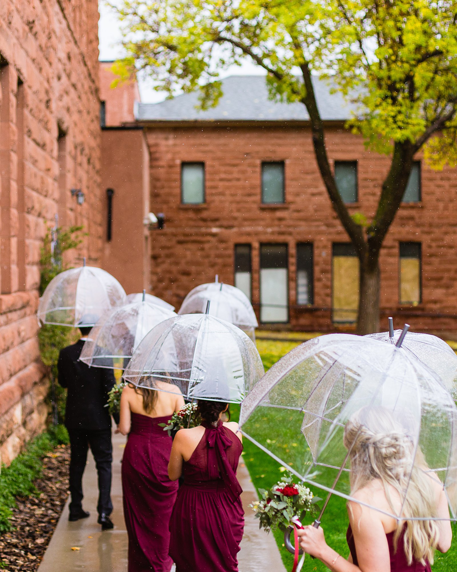 Bridal party walk with umbrellas on a rainy wedding day by Flagstaff wedding photographer PMA Photography.