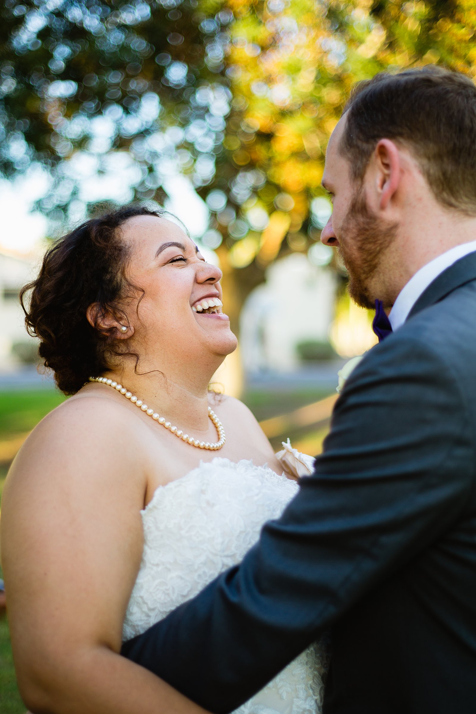 Bride and groom laughing together during their Encanto Park wedding by Phoenix wedding photographer PMA Photography.