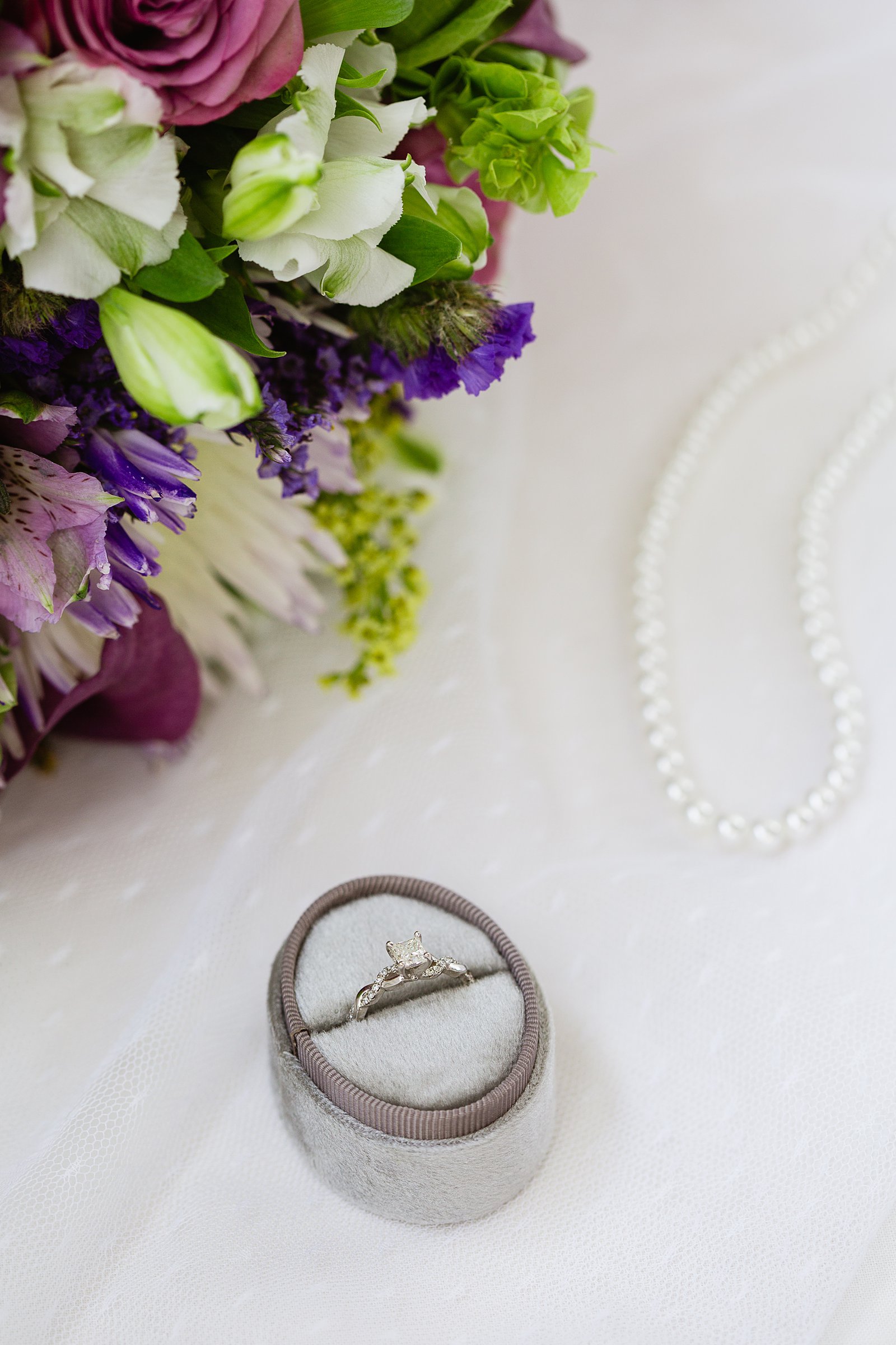 Brides's wedding day details of a classic wedding ring and string of pearls by PMA Photography.