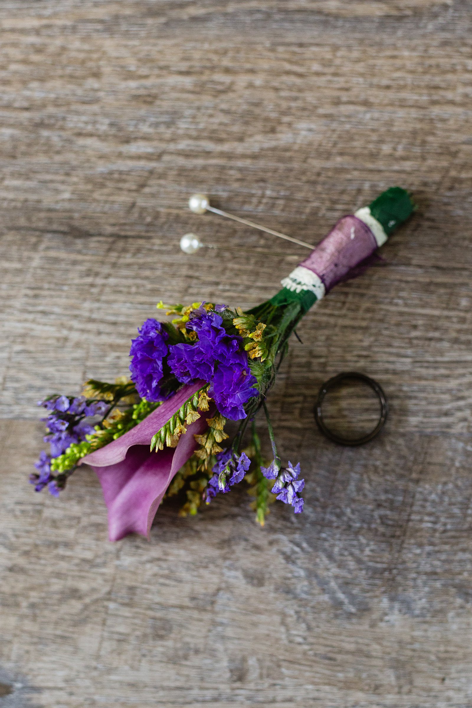 Groom's wedding day details of purple boutonniere and black wedding band by PMA Photography.