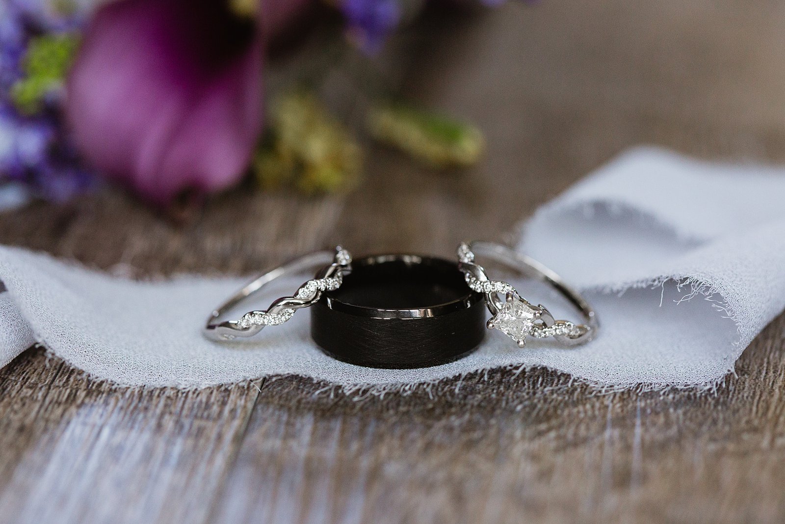 Bride and grooms simple white gold and black wedding bands by PMA Photography.
