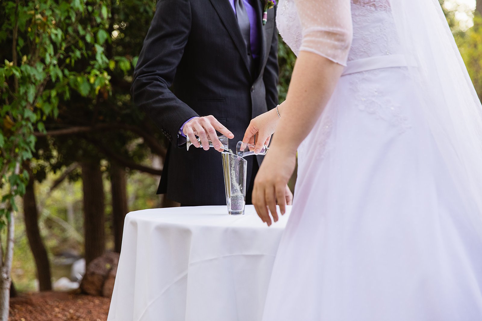 Bride and groom mixing pieces of glass together during their blown glass unity ceremony by PMA Photography.