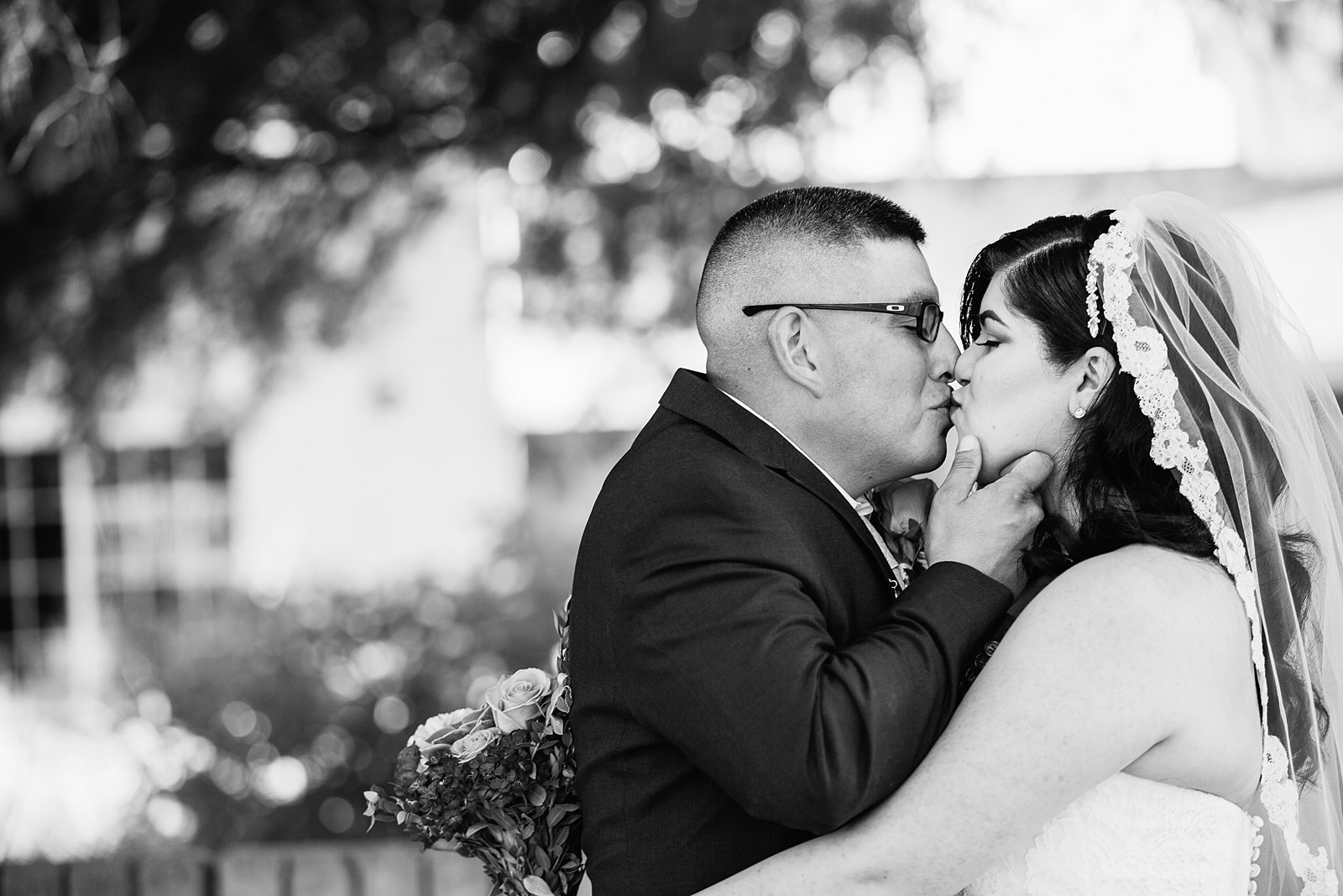 Bride and groom share a kiss during their The Farmhouse at Schnepf Farms wedding by Queen Creek wedding photographer PMA Photography.