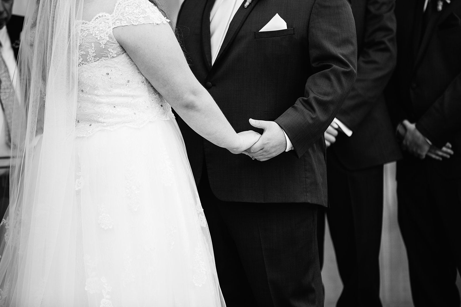 Bride and groom holding hands during their backyard wedding ceremony by PMA Photography.