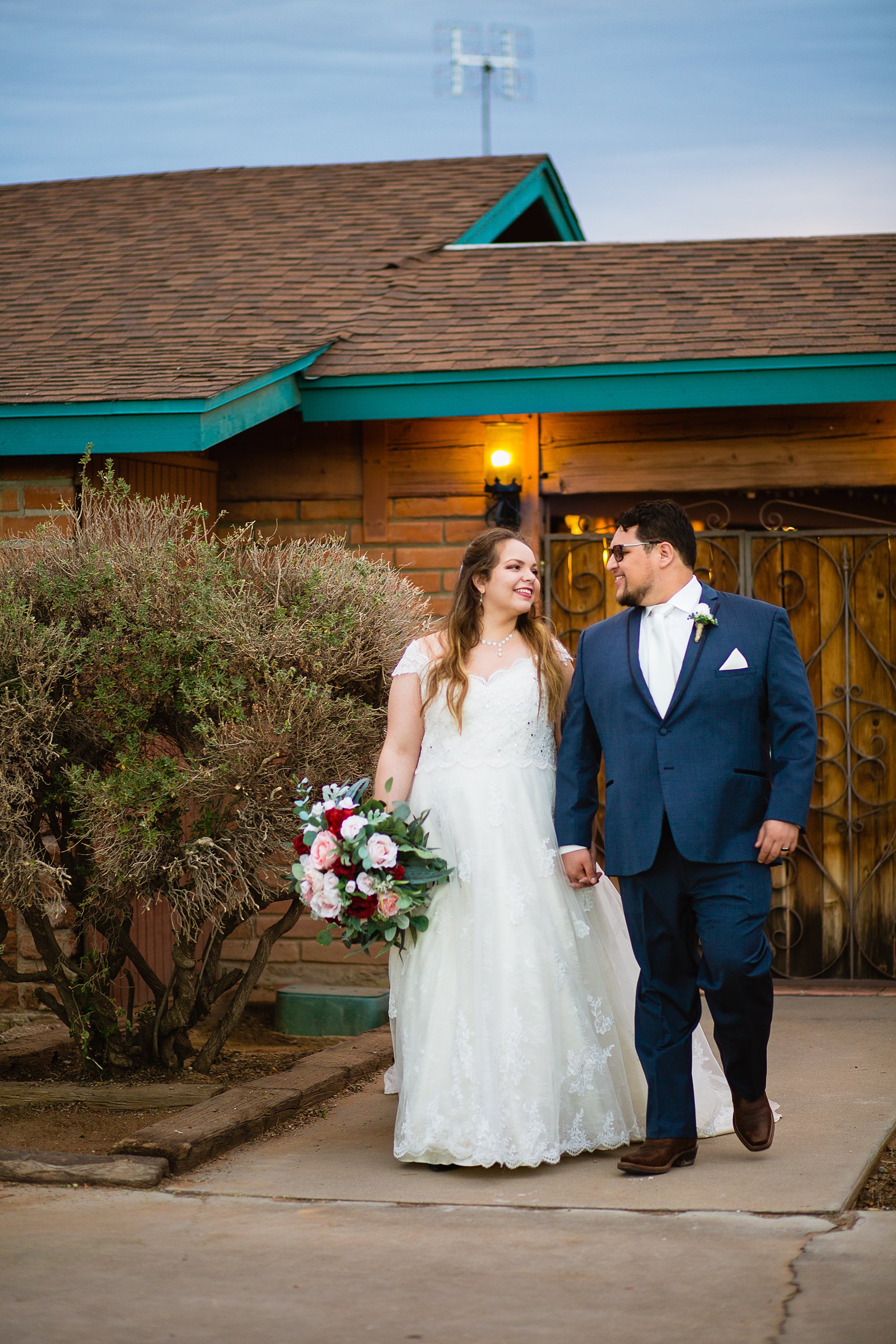 Bride and Groom walking together during their Backyard wedding by Casa Grande wedding photographer PMA Photography.