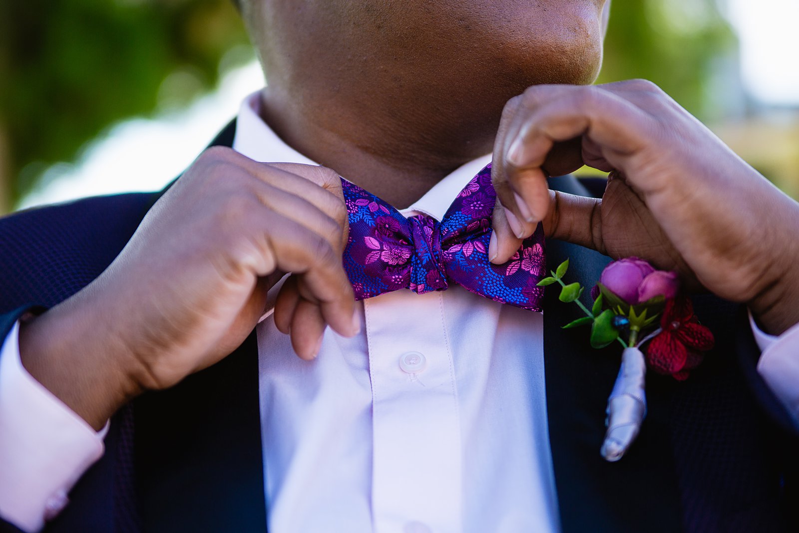 Bride adjusting her purple floral bow tie while getting ready for her wedding by Arizona wedding photographers PMA Photographer