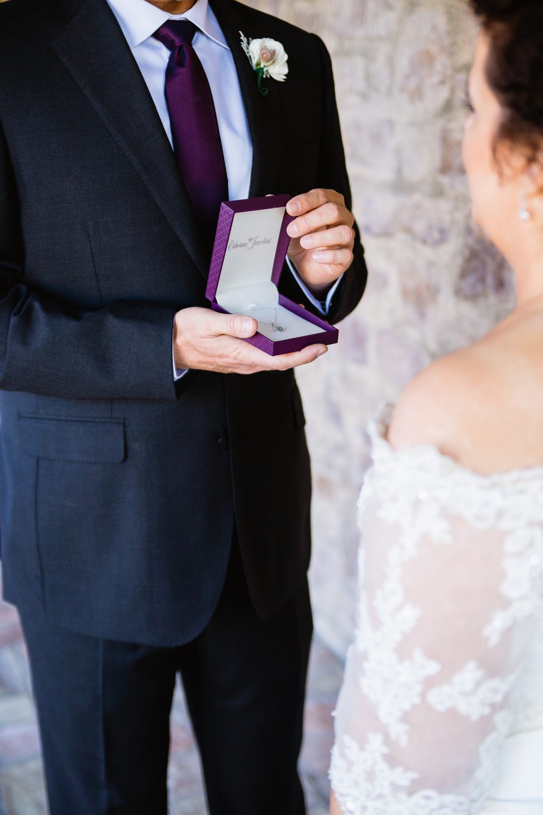 Groom surprising his bride with a necklace during their first look by PMA Photography.