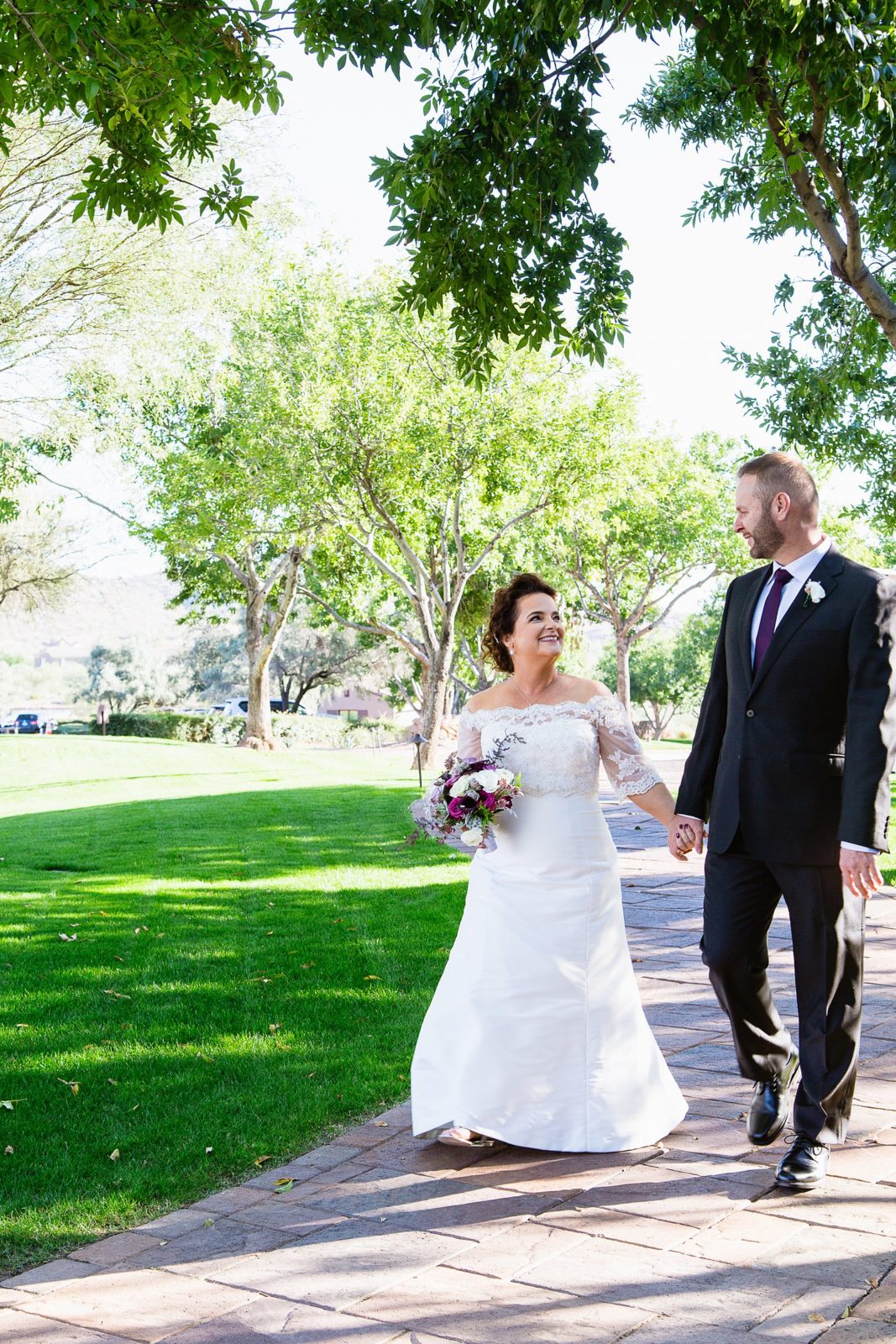 Bride and groom walking together during their Superstition Mountain Clubhouse wedding by Mesa wedding photographer PMA Photography.