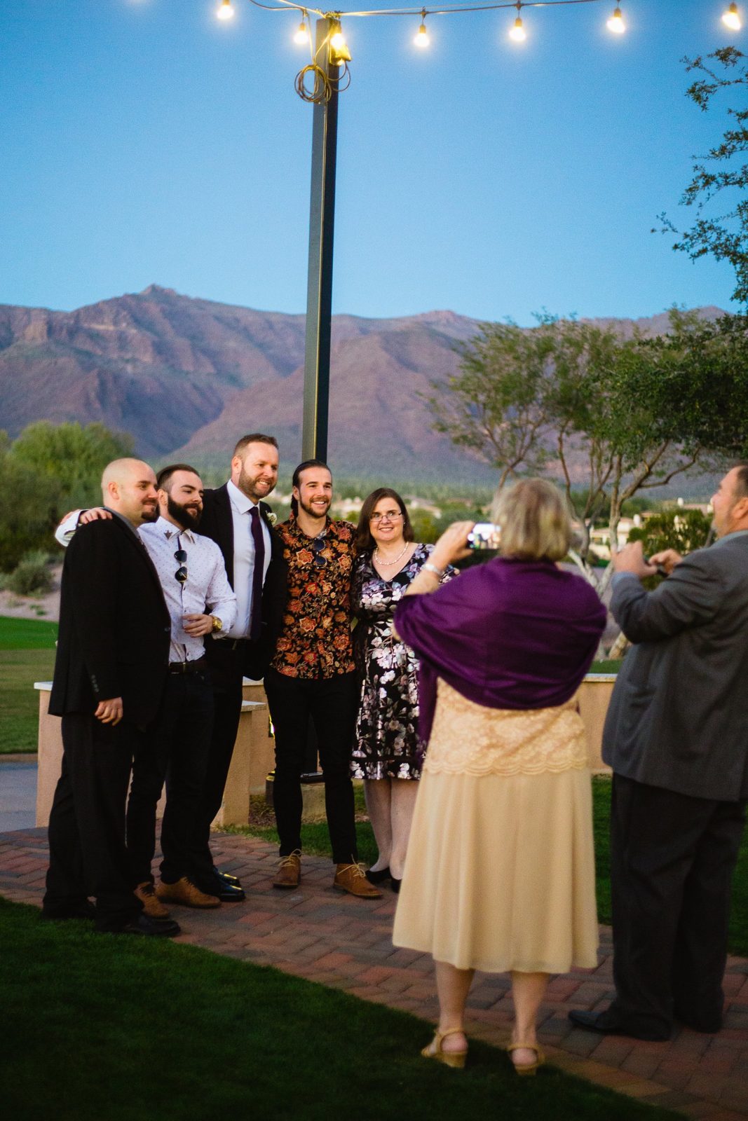 Guests taking a photo with the groom during cocktail hour by PMA Photography.