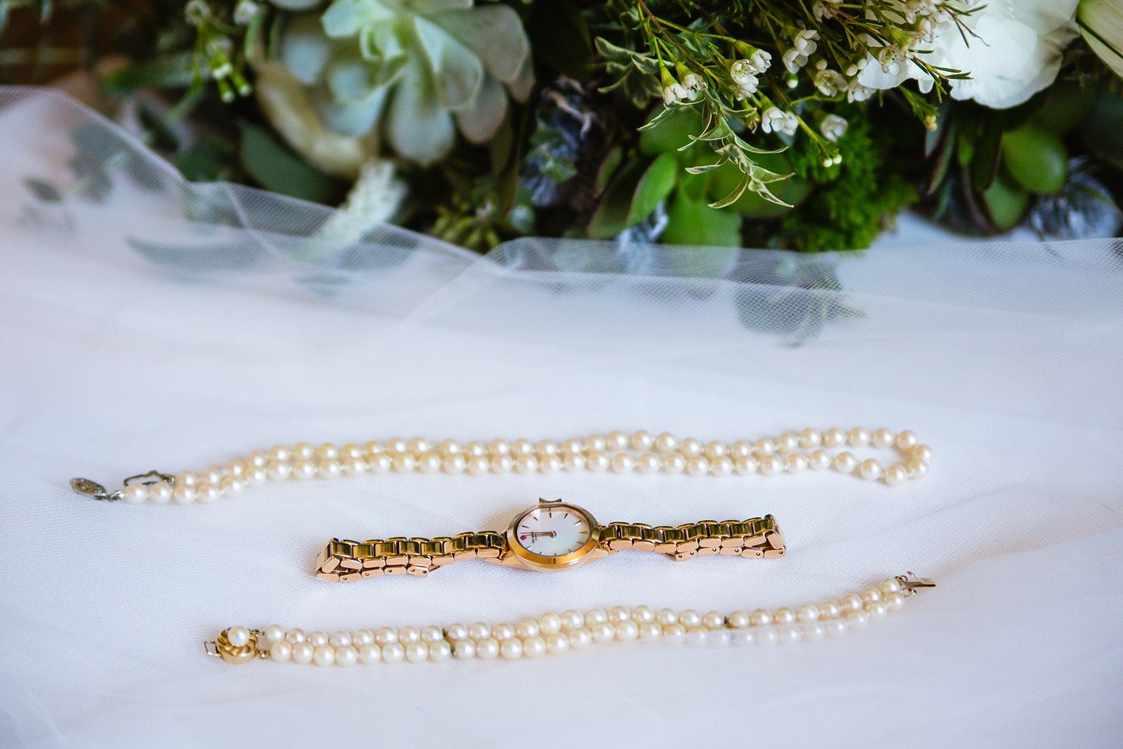 Brides's wedding day details of pearl necklace and bracelet with gold watch by PMA Photography.