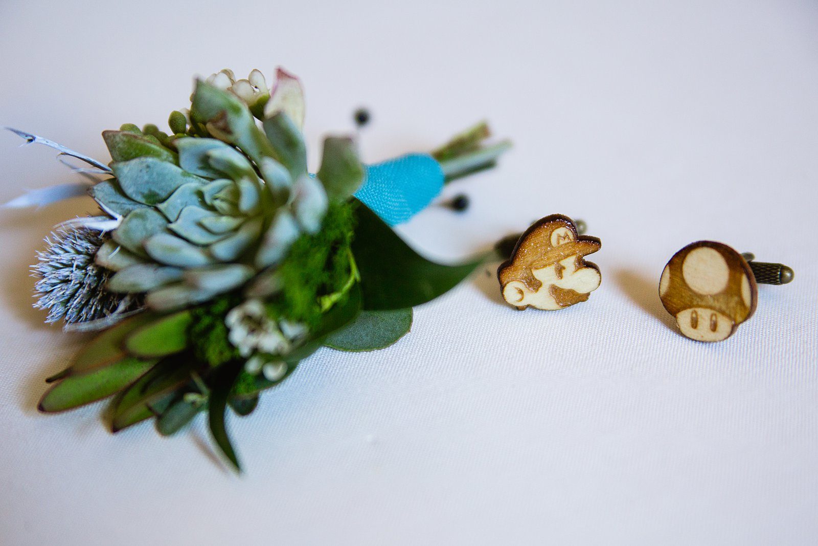 Groom's succulent boutonniere and wooden Mario Bros cuff links by PMA Photography.