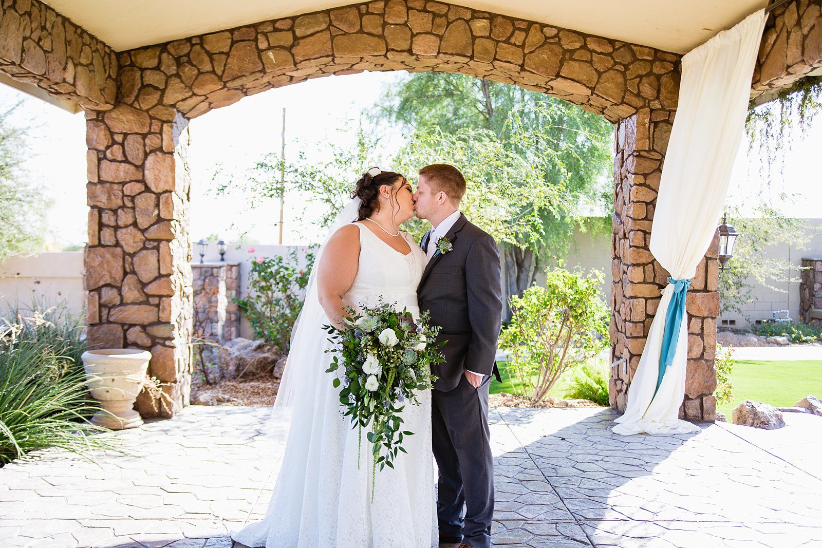 Bride and Groom share a kiss during their Superstition Manor wedding by Mesa wedding photographer PMA Photography.