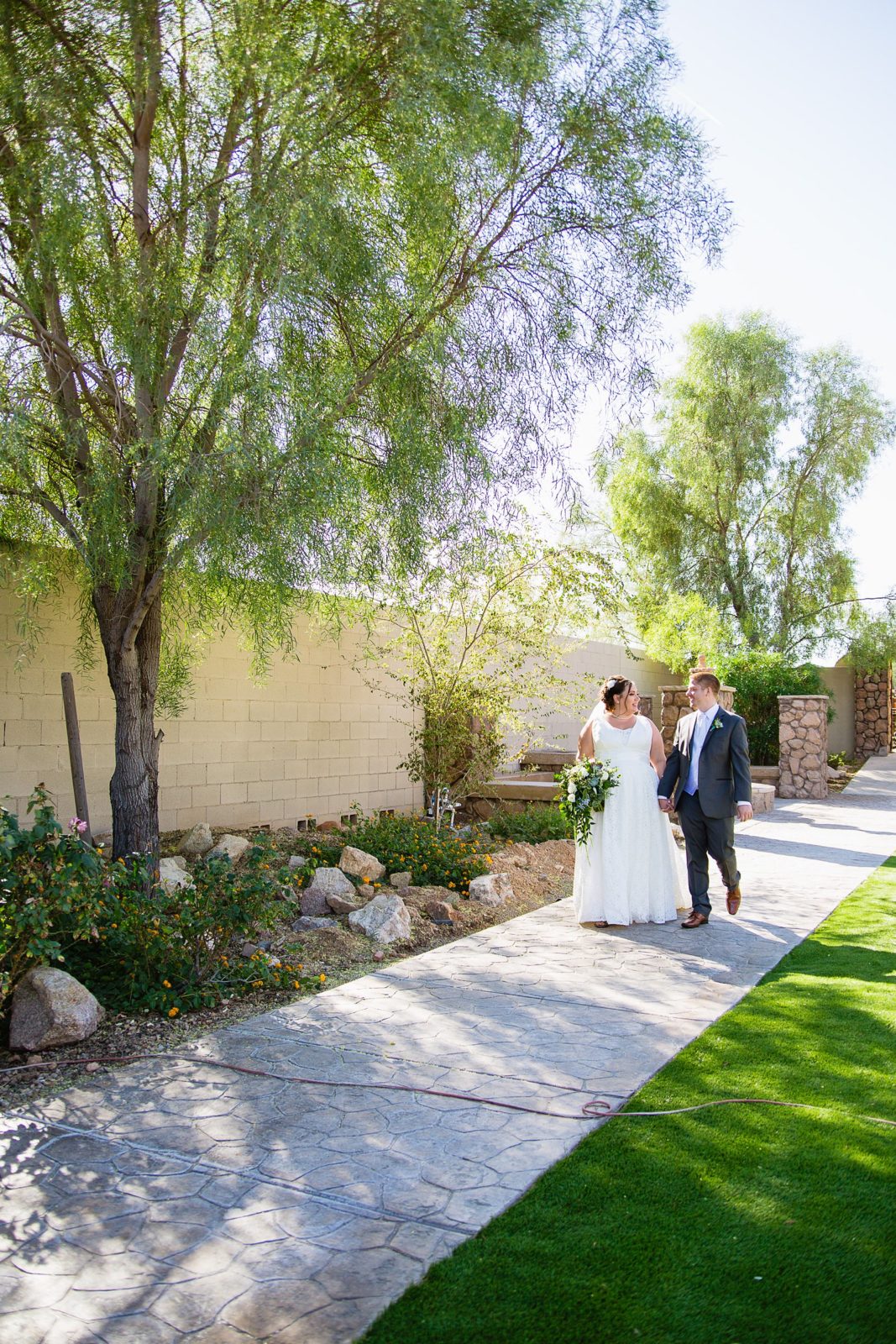 Bride and Groom walking together during their Superstition Manor wedding by Arizona wedding photographer PMA Photography.