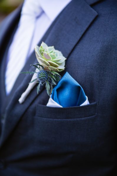 Groom's succulent and blue thistle boutonniere with blue and white pocket square by PMA Photography.