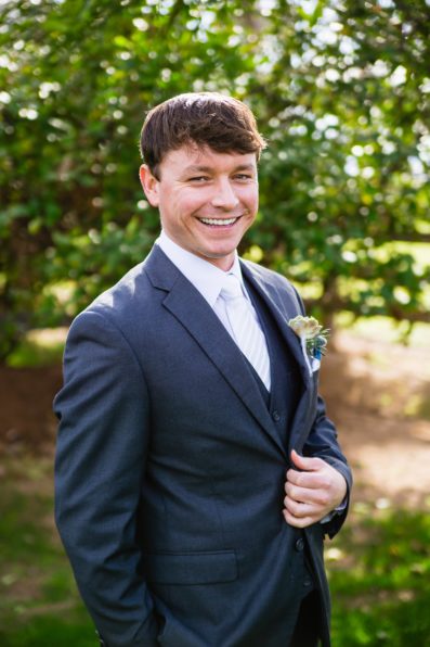 Groom in a grey and white suit smiling at his Venue at the Grove wedding by PMA Photography.