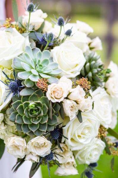 Bride's succulent, cream rose, and blue thistle wedding bouquet by PMA Photography.