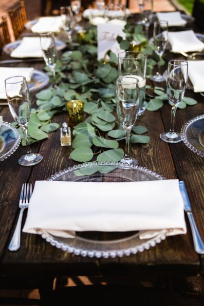 Rustic eucalyptus and candle table setting with cream napkins by PMA Photography.