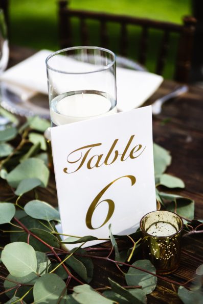 Rustic eucalyptus and candle centerpieces and table numbers at Venue At The Grove wedding reception by Phoenix wedding photographer PMA Photography.