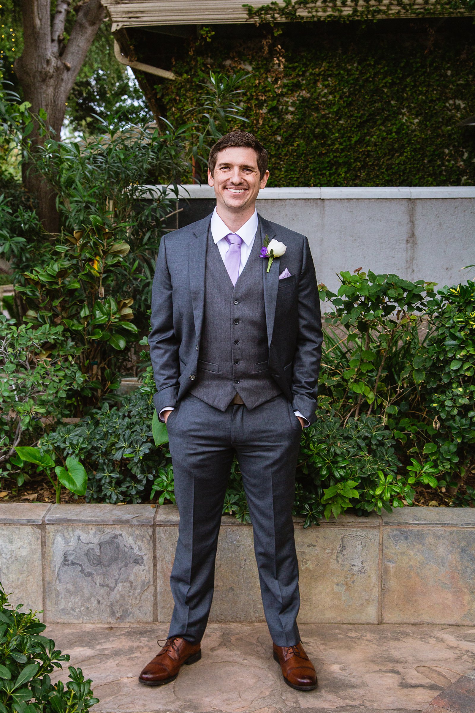 Groom in a dark grey suit with lilac tie on his wedding day by PMA Photography.