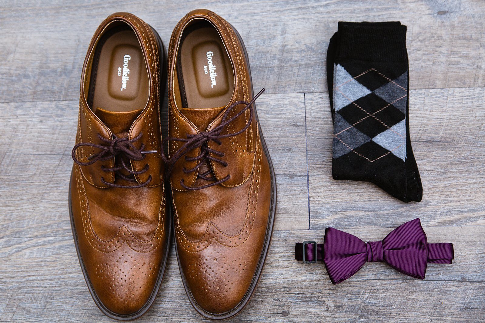 Groom's wedding details of brown oxfords, argyle socks, and a purple bow tie by PMA Photography.