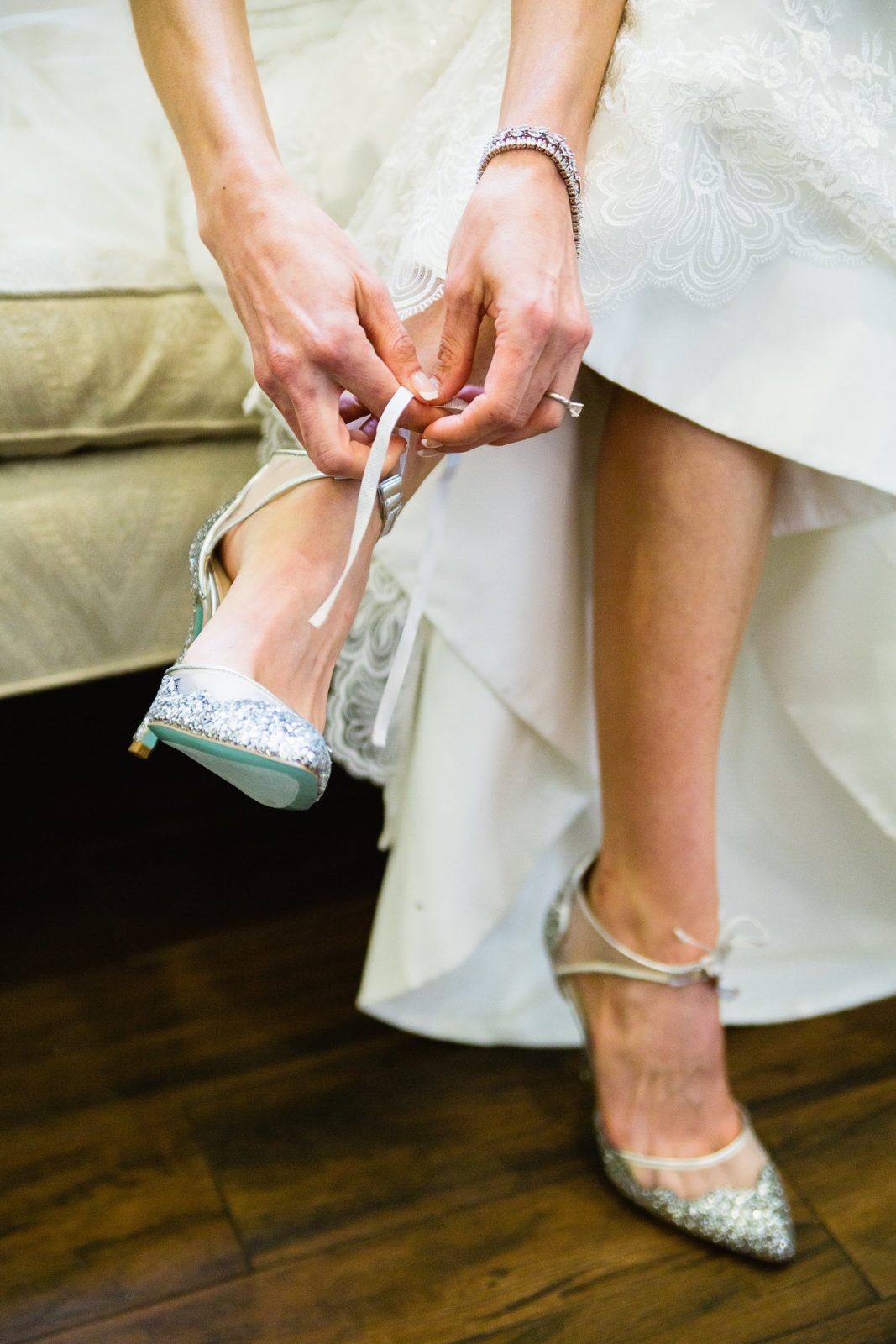 Bride tying her sparkly Betsy Johnson wedding heals while getting ready by PMA Photography.