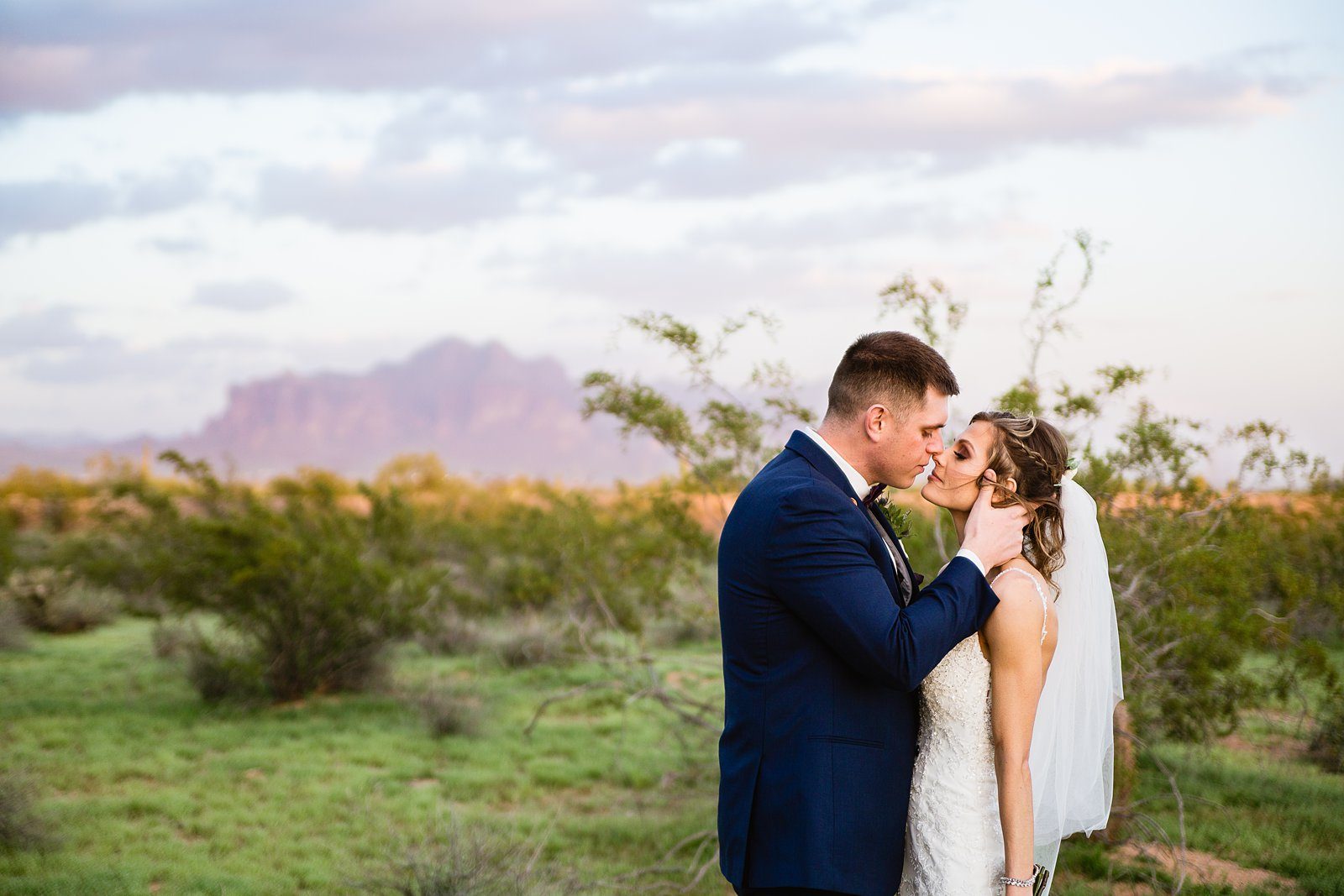 Bride and groom together in the desert with the Superstition Mountains by Arizona wedding photographer PMA Photography.