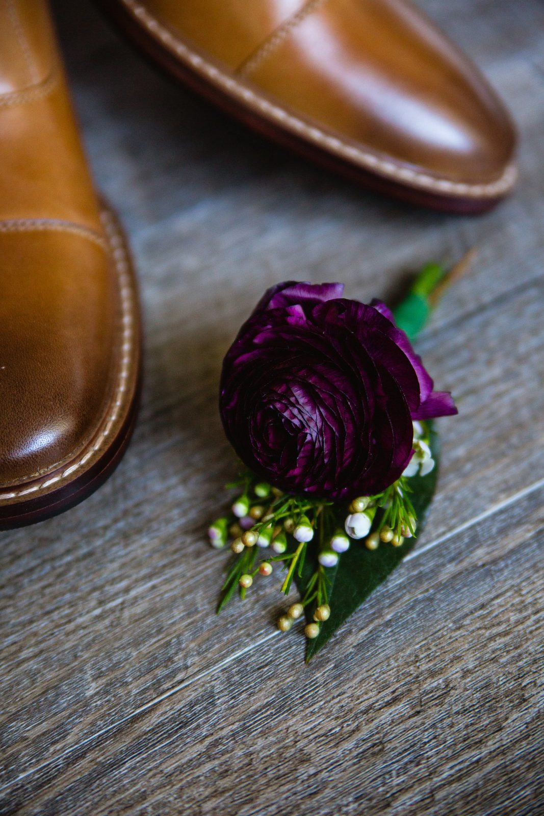 Groom's romantic purple ranunculus and wax flower groom's boutonniere.