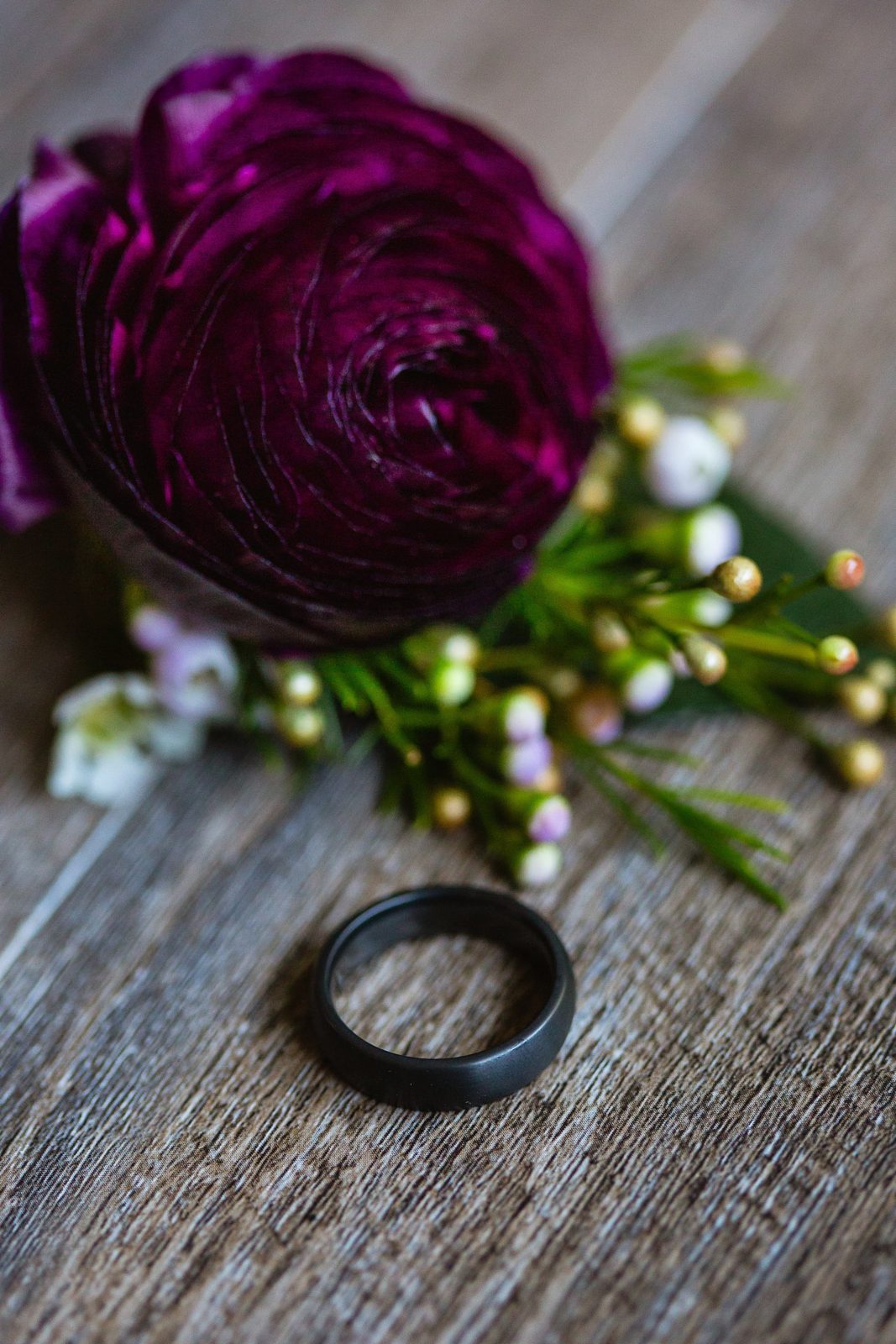 Groom's dark grey wedding ring and burgundy boutonniere by PMA Photography.