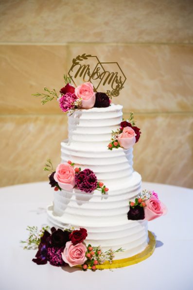Simple wedding cake with pink and burgundy florals by Arizona wedding photographer PMA Photography.