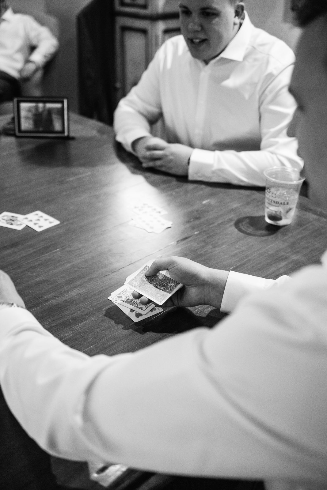 Groom and groomsmen playing cards before the wedding ceremony by PMA Photography.