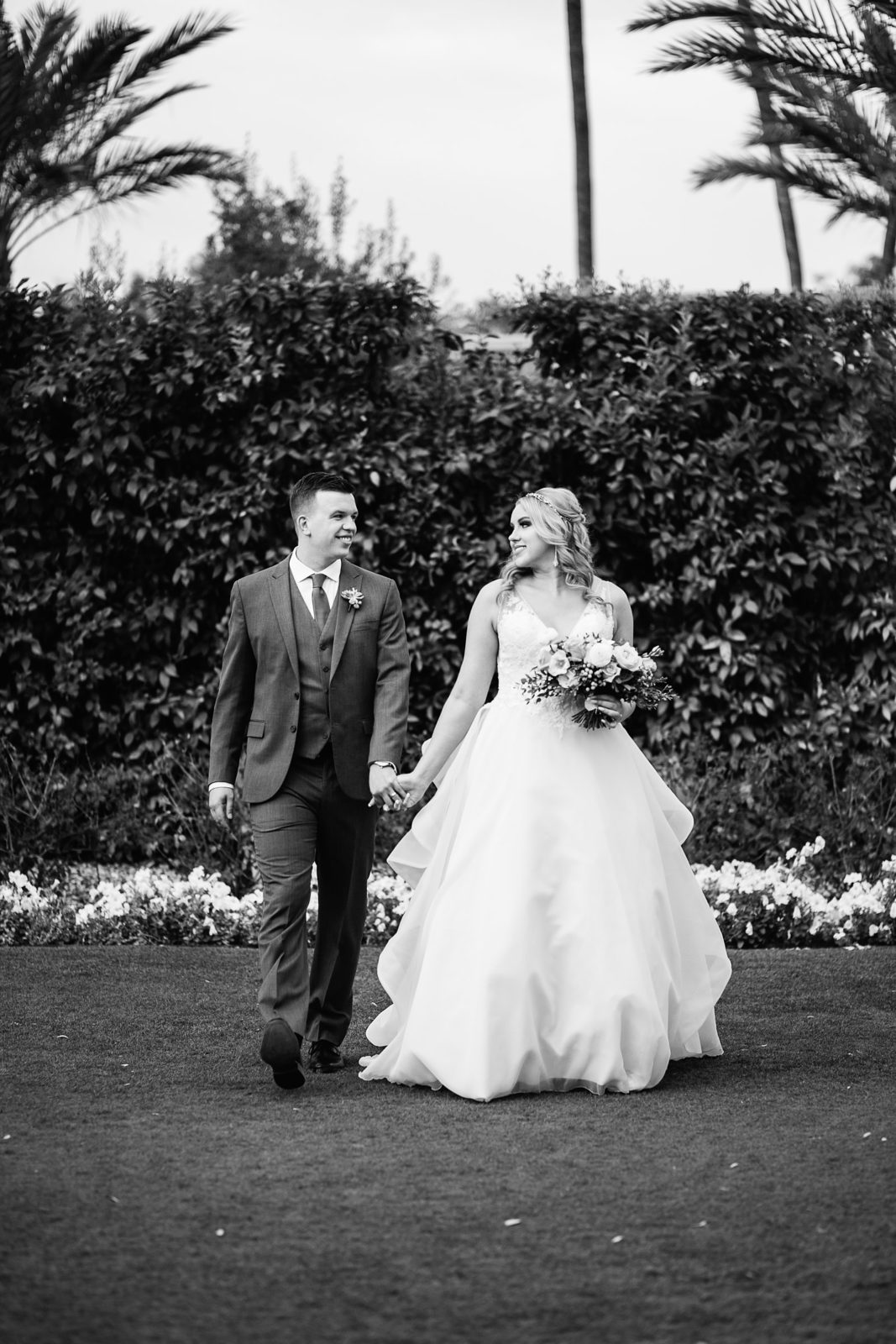 Bride and Groom walking together during their The Scottsdale Resort at McCormick Ranch wedding by Scottsdale wedding photographer PMA Photography.