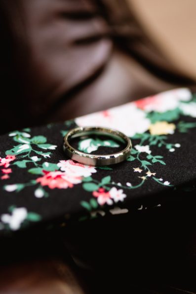 Simple white gold wedding band on a floral tie by PMA Photography.