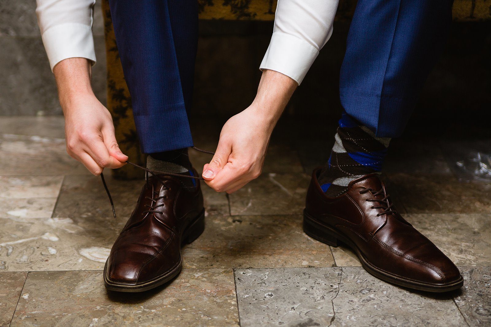 Groom putting on his shoes while getting ready for his wedding day by PMA Photography.