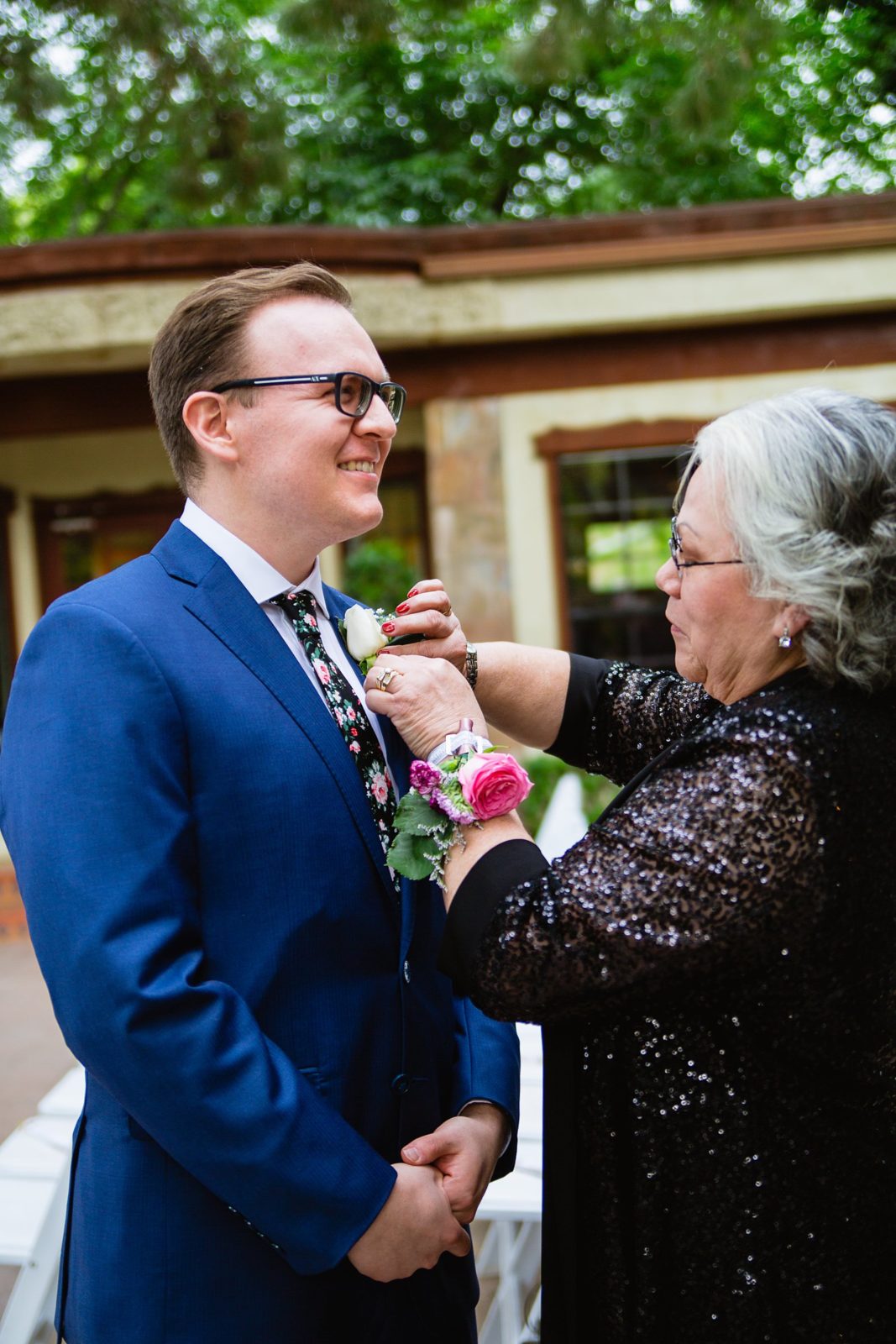 Groom's mother pinning on his boutonniere while getting ready for his wedding day by PMA Photography.