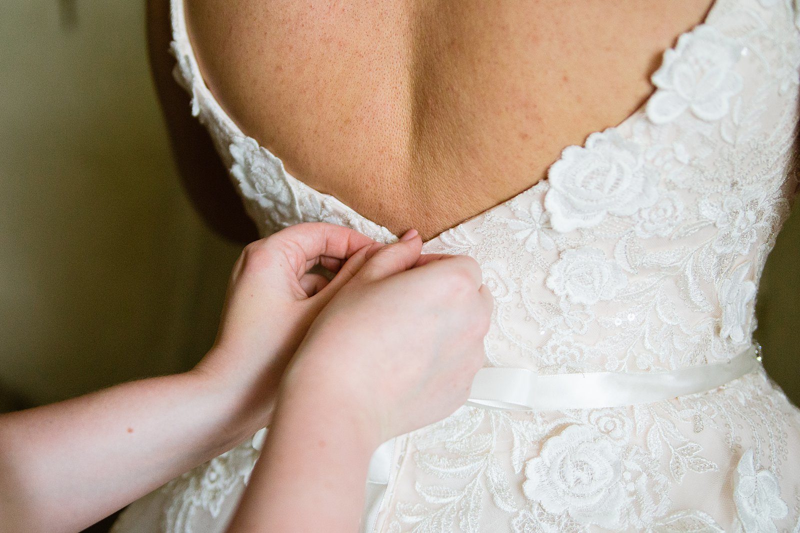 Buttoning up a romantic garden inspired wedding dress by PMA Photography.