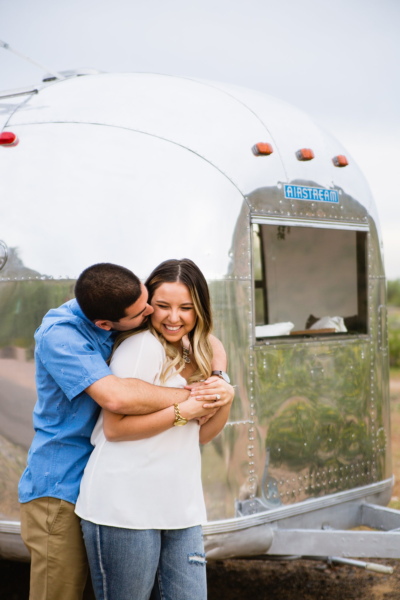 Couple laugh together during their Air Stream engagement session by Phoenix engagement photographer PMA Photography.